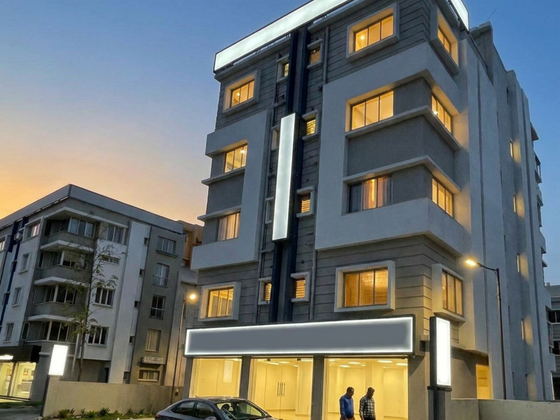 Photograph of 362 Barkhola at dusk, its upper floors and retail units lit